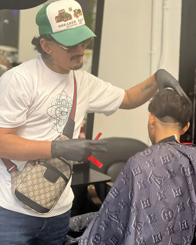 A barber at work, shears in hand, a boy in the chair