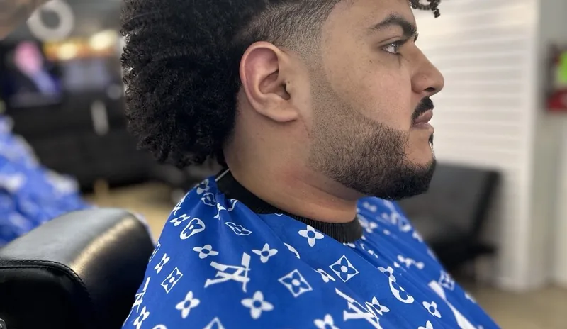 A curly top with a skin fade, in the chair at Catracho's
